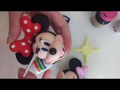 a person holding a toothbrush in front of mickey mouse and minnie mouse cake decorations