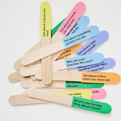 a group of wooden clothes pins with different colored paper stick sayings on them, sitting next to each other