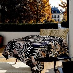 a bed sitting on top of a hard wood floor next to a window covered in black and white sheets