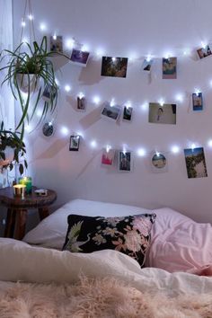 a bedroom with lights strung from the ceiling and pictures on the wall above the bed