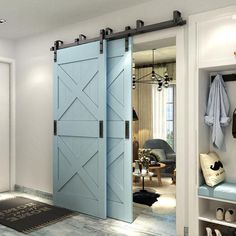 a blue barn door is opened to reveal a living room with white walls and wood floors