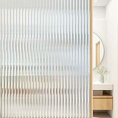 an open door with vertical blinds on the outside and inside, in front of a mirror