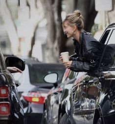 a woman standing next to a car holding a cup