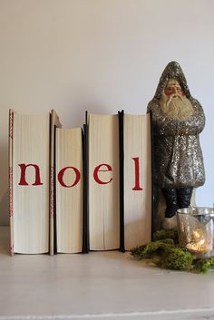 there are three books on the shelf with santa claus next to them and a candle