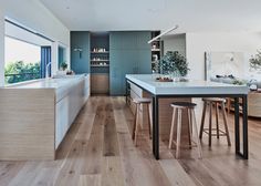 a kitchen with wooden flooring and white counter tops next to an island in front of a window