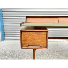 an old wooden desk sitting on top of a cement floor next to a garage door