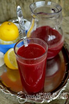 two glasses of juice on a plate with lemons in the background