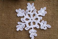 a crocheted snowflake laying on top of a green surface next to a wall