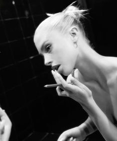 a woman is brushing her teeth in front of a mirror