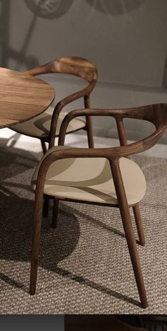 two wooden chairs sitting next to each other on top of a carpeted floor in front of a wall