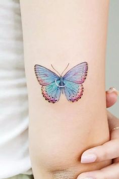 a woman's arm with a blue butterfly tattoo on the left side of her body