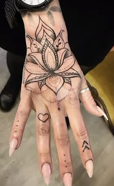 a woman's hand with tattoos on it and a clock in the back ground