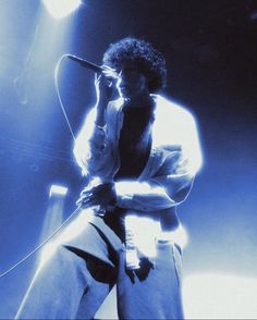 a man standing in front of a microphone on top of a stage with lights behind him