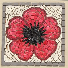 a red and black flower made out of small bricks on top of a tile wall