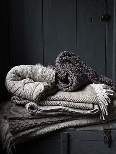 a pile of blankets sitting on top of an old trunk in front of a wooden door