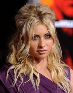 a woman with long blonde hair wearing a purple dress and looking off to the side