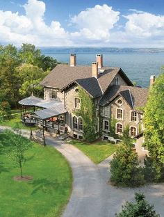 an aerial view of a large house with trees and water in the backround