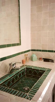 a bathroom sink with green and white tiles