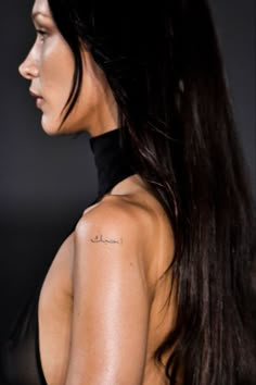 the back of a woman's shoulder with tattoos on her left arm and chest