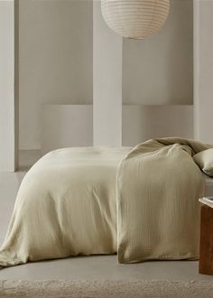 a bed with beige sheets and pillows in a room