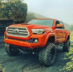 an orange toyota truck parked on the side of a road in front of some rocks