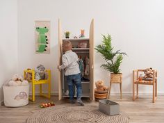 a little boy standing in front of a toy cabinet