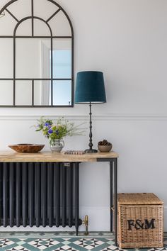 a room with a table, mirror and basket on the floor in front of it