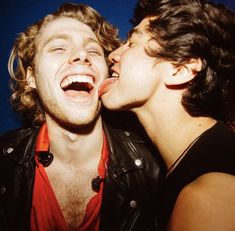 two young men are kissing each other with their mouths open