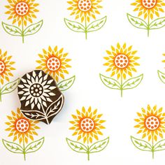 an orange and green flower on a white wallpaper with yellow flowers in the background