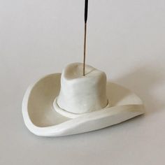 a small white hat with a black stick sticking out of it's centerpiece