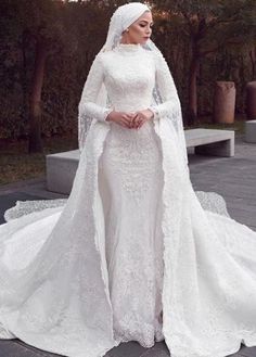 a woman wearing a white wedding gown with long sleeves and a veil on her head