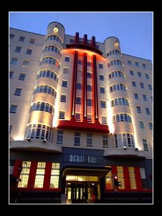 the hotel is lit up at night with red and white lights on it's side