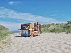 a woman sitting in a chair on top of a sandy beach