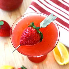 a close up of a drink in a glass on a table with strawberries and lemons