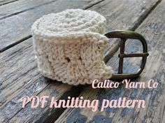 a crocheted hat with a metal buckle on top of a wooden table next to the words calico yarn co knitting pattern