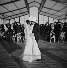 black and white photo of bride and groom kissing in front of large group of people