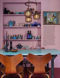 two wooden chairs sitting at a table in front of a shelf filled with bottles and bowls