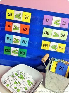 a blue board with numbers on it next to a bowl of cards and a bucket of pencils