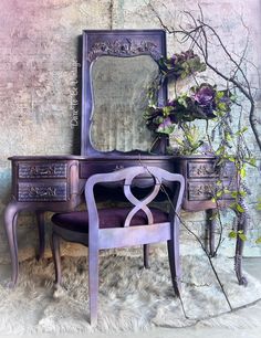 an antique vanity with mirror and purple chair in front of it, next to a potted plant