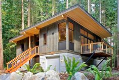 a small house in the woods surrounded by rocks and trees with stairs leading up to it