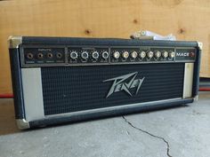 an amp sitting on the ground in front of a wooden wall