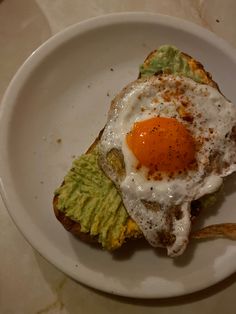 an egg and avocado toast on a white plate