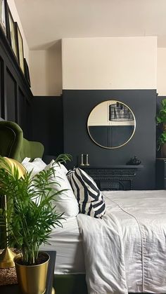 a bedroom with black walls, white bedding and potted plants on the floor