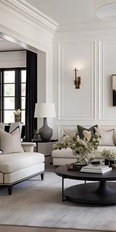 a living room filled with white furniture and black curtains on the windows sills