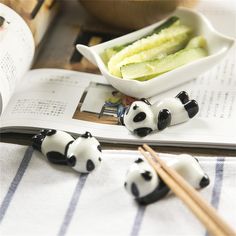 three little panda bears sitting on top of a table next to some chopsticks