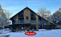 a house with snow on the ground in front of it and a balconette sign