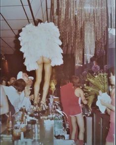 an old photo of a woman standing on top of a table in a bar with other people