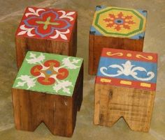 three wooden stools with painted designs on them sitting next to each other in front of a stone floor