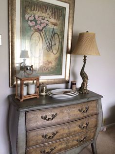 an old dresser has a flower shop sign above it and a lamp next to it