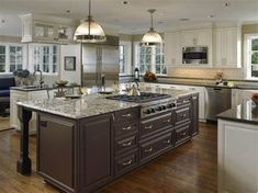 a large kitchen with an island in the middle and two pendant lights hanging from the ceiling